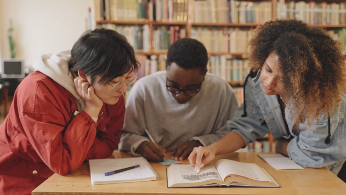 young people reading, scribbling and discussing book together